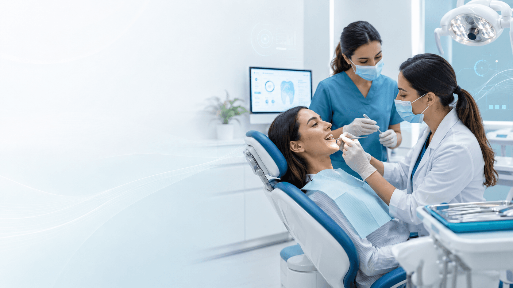A patient in a dental chair speaking with a dentist and assistant, with a tooth diagram shown on a nearby screen